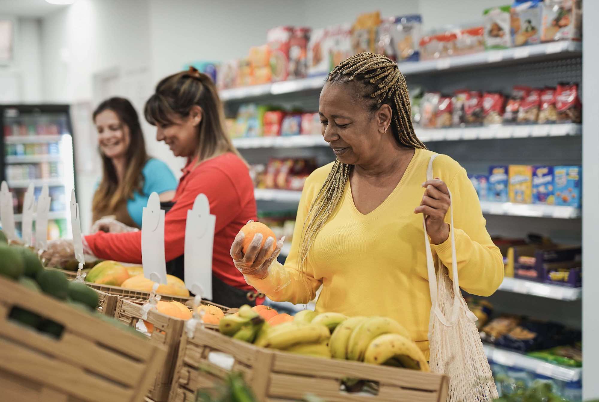 African senior woman buying fresh organic fruits at supermarket